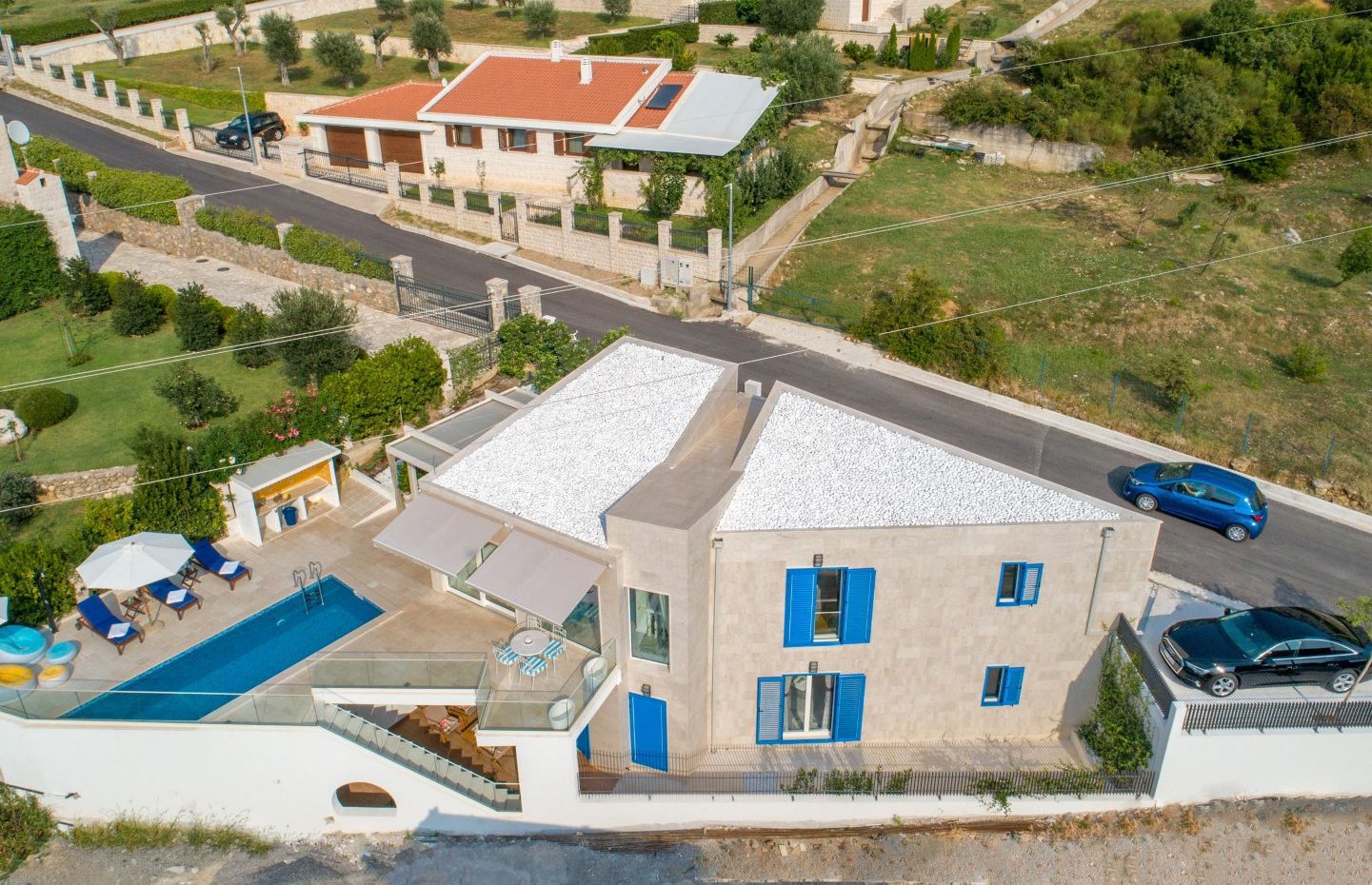 Two-story villa with a pool, terrace, and blue shutters in Blizikuće, Montenegro: aerial view of the house and grounds.