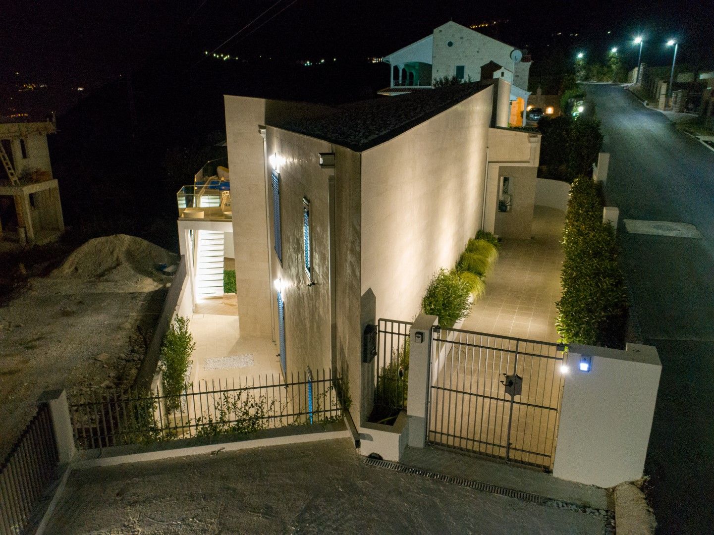 Modern villa with night lighting and a swimming pool in Blizikuće, Montenegro: exterior view of the house with a fenced area.