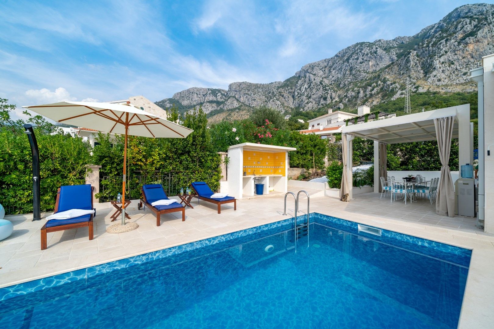 Pool with sun loungers, barbecue area, and mountain views by the house in Blizikuće, Montenegro.