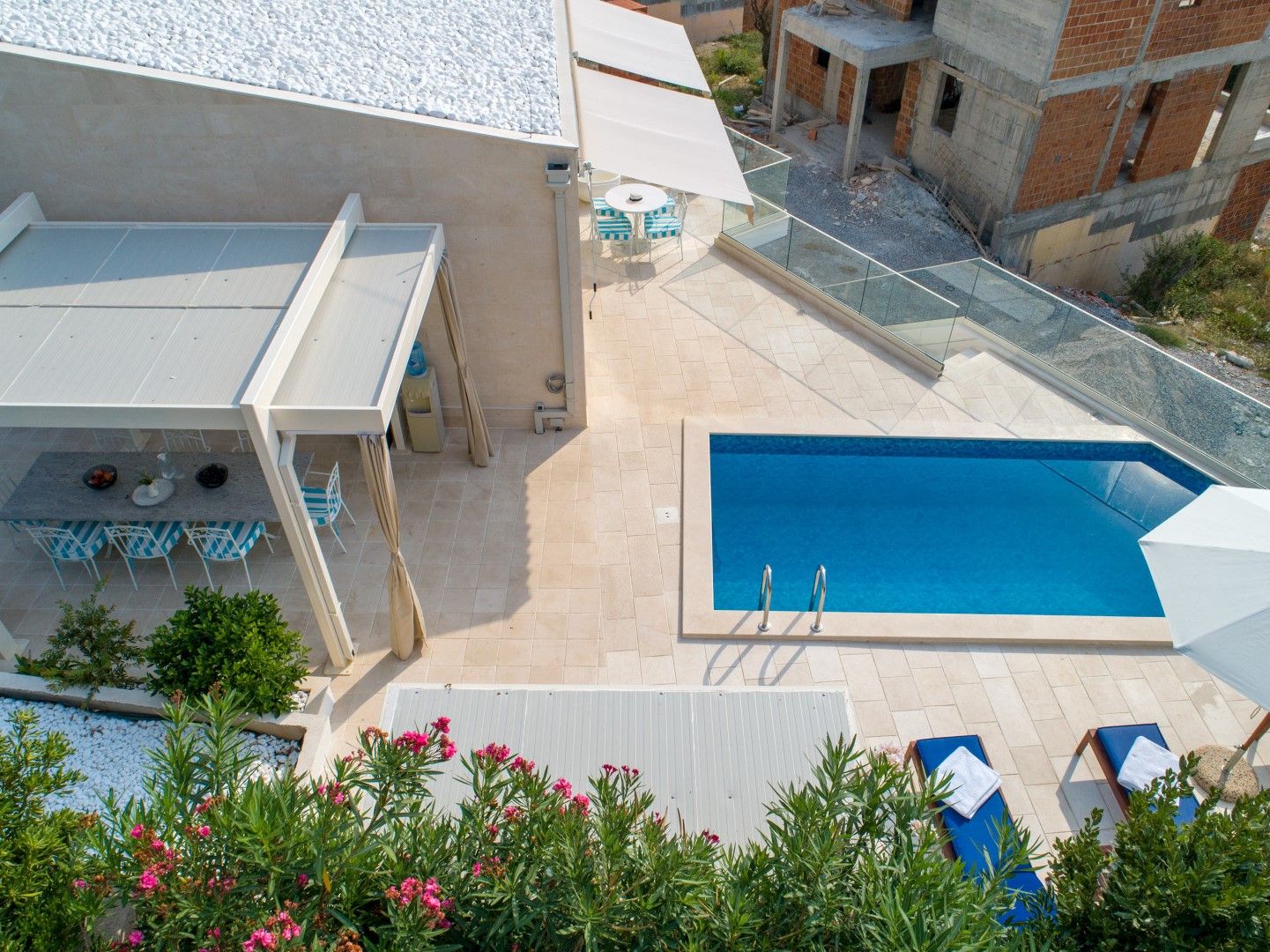 Terrace of a house in Blizikuće, Montenegro: pool, covered dining area, sun loungers, and garden view.