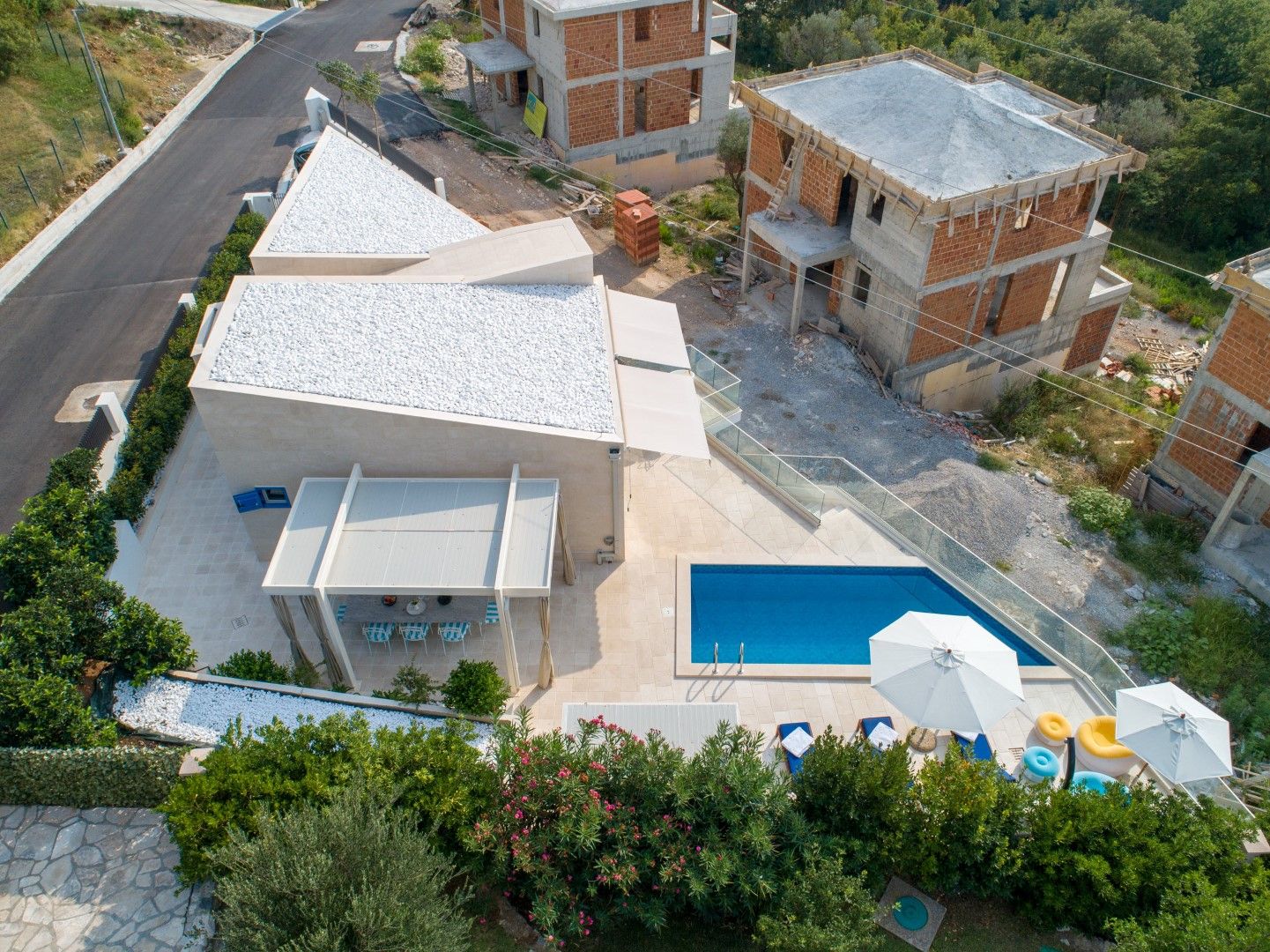 Modern villa in Blizikuće, Montenegro: top view of the pool, terrace with pergola, and landscaped grounds.