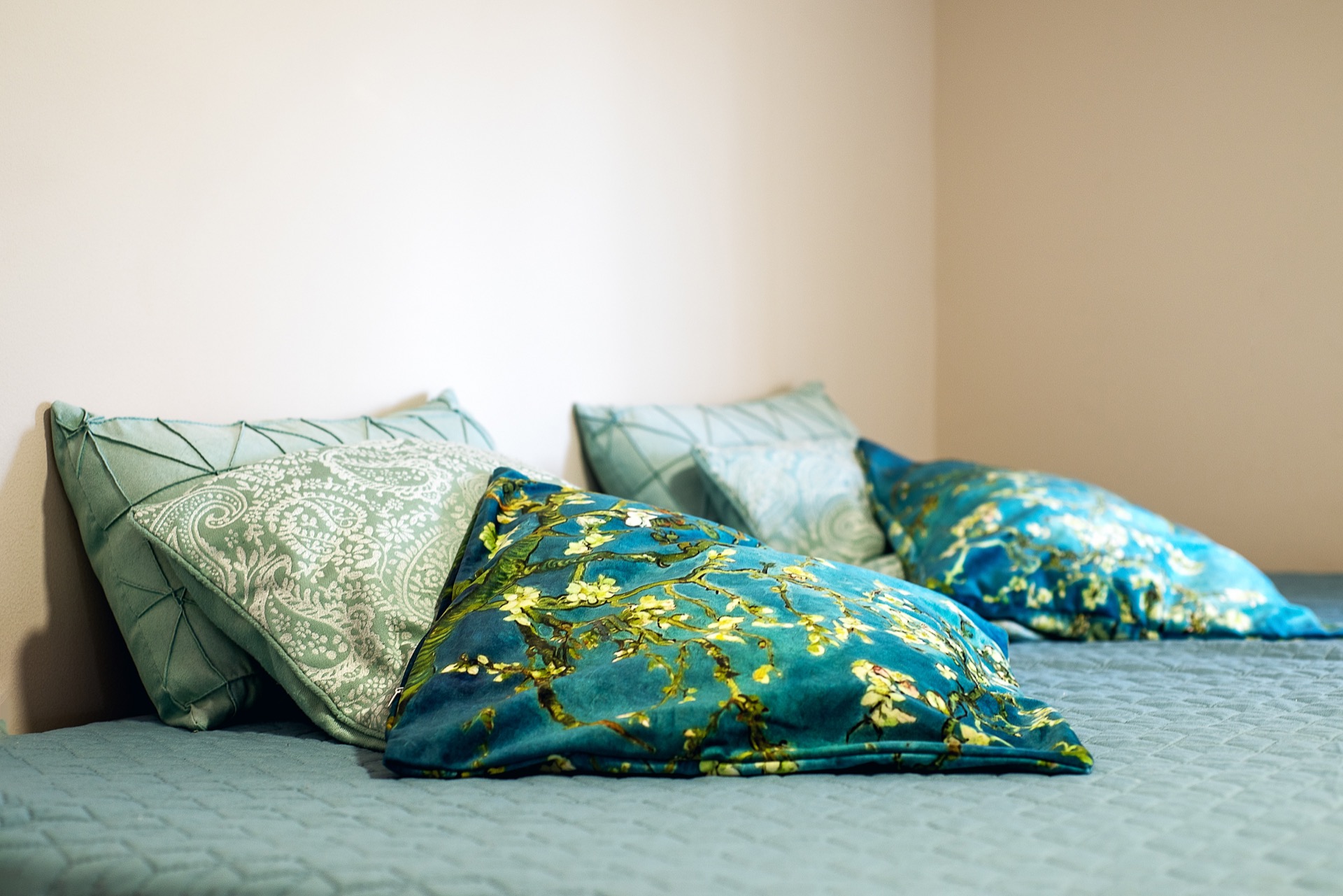 Cozy bedroom in an apartment in Budva, Montenegro: a bed with decorative pillows in turquoise tones and light walls.
