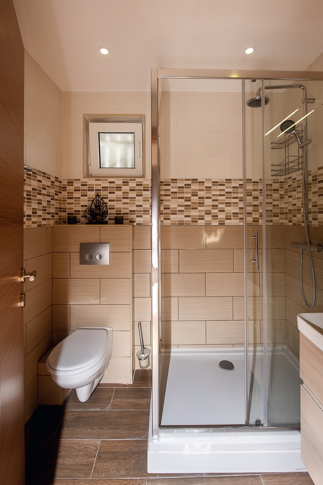 Modern bathroom in an apartment in Budva, Montenegro: shower cabin, wall-mounted toilet, and beige tiles.