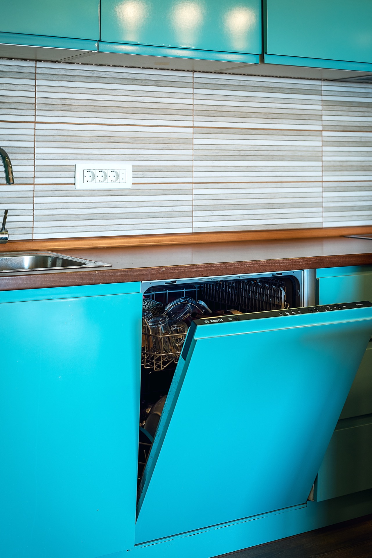 Modern kitchen with turquoise cabinet fronts and a Bosch dishwasher in an apartment for sale in Budva, Montenegro.