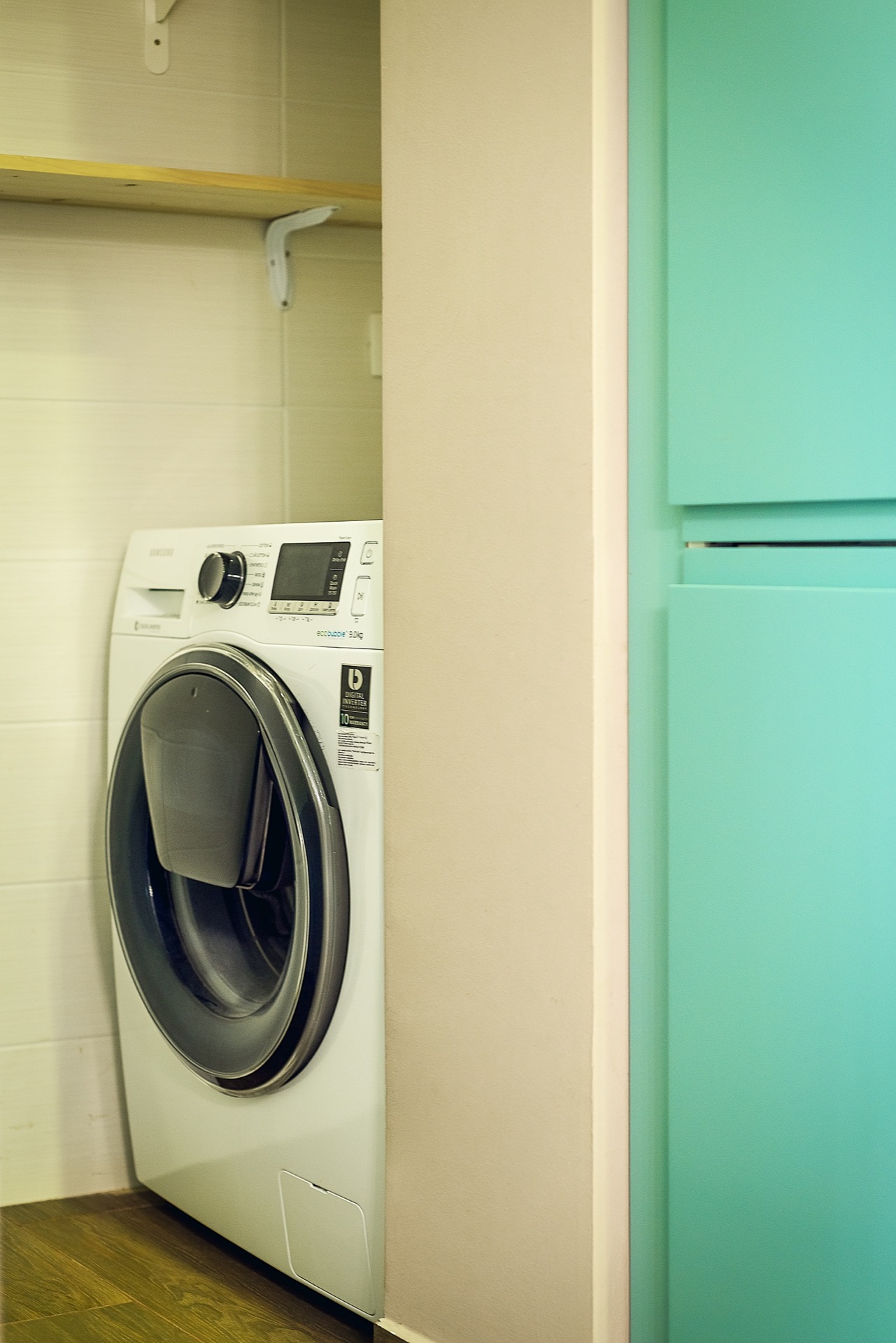 Samsung washing machine in a niche with a shelf in an apartment in Budva, Montenegro: modern appliances and interior.