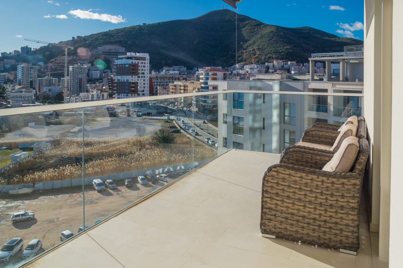 Balcony with wicker furniture and panoramic views of the city and mountains in an apartment, Budva, Montenegro.
