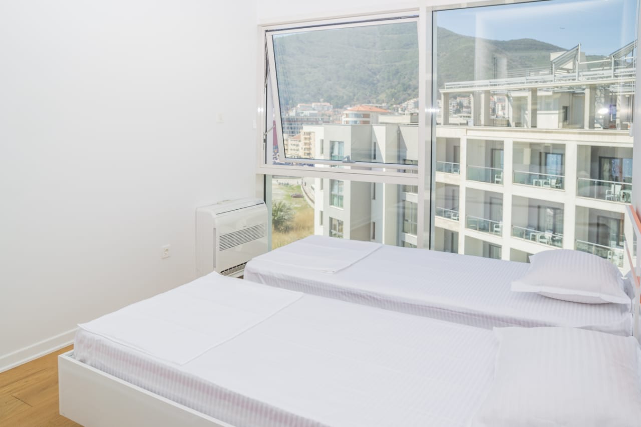 Bright bedroom with two beds and panoramic mountain views in an apartment in Budva, Montenegro.
