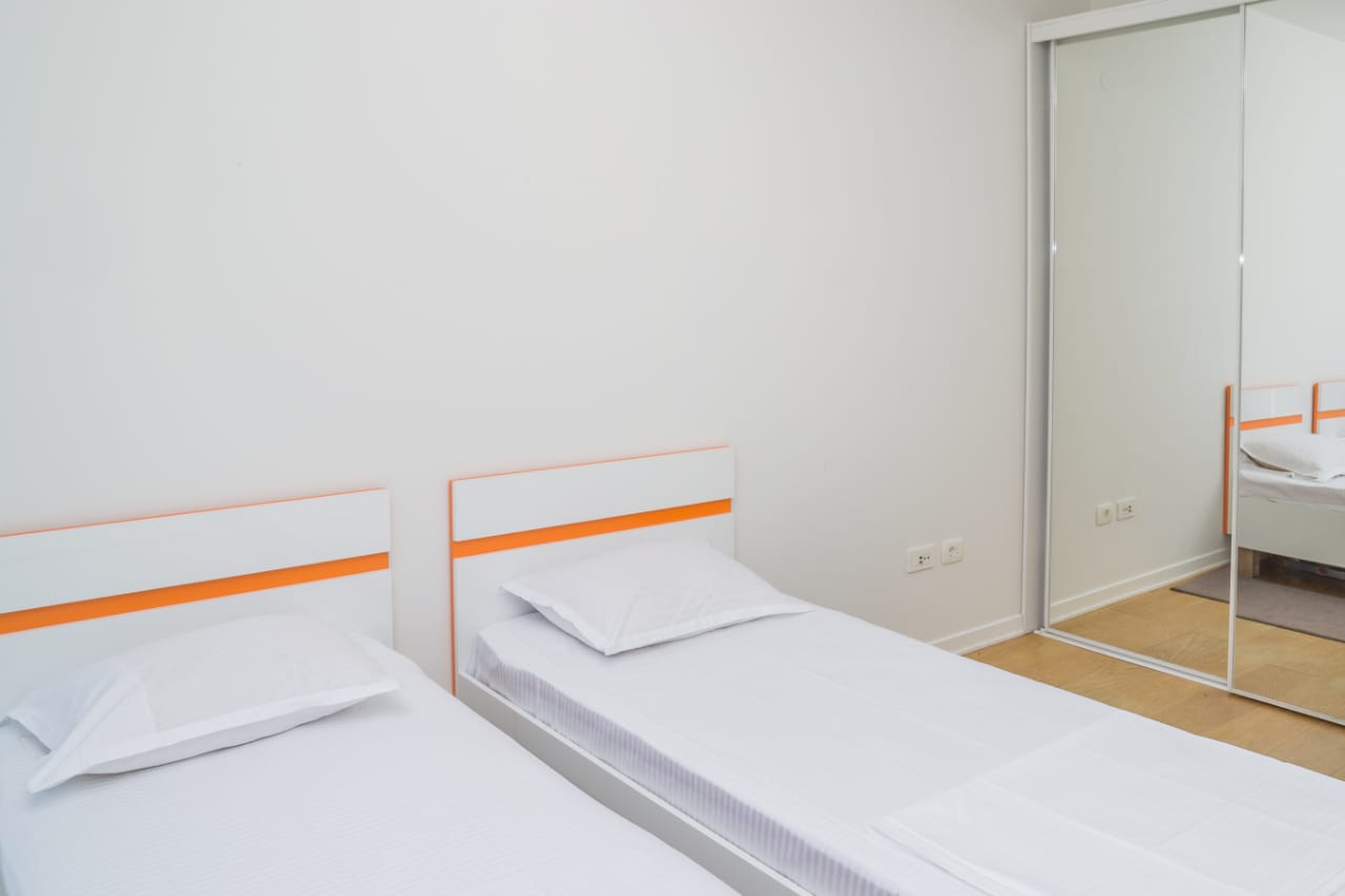 Bright bedroom with two single beds and a mirrored sliding wardrobe in an apartment, Budva, Montenegro.