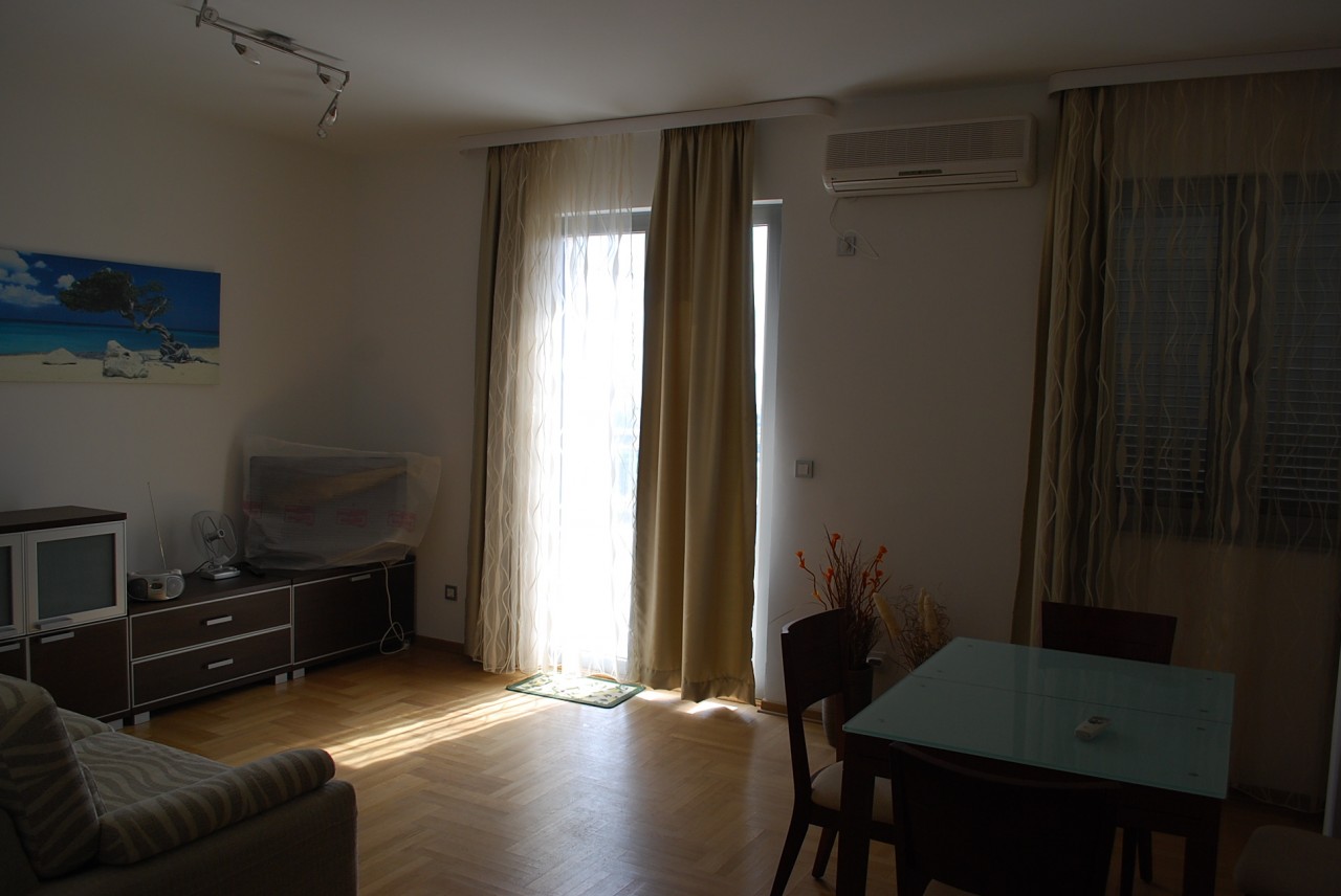 Bright living room with furniture, parquet flooring, and access to the balcony in an apartment in Budva, Montenegro. Modern interior.