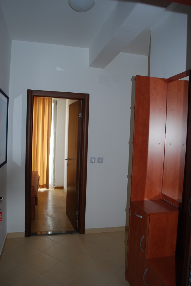 Hallway with wooden furniture in apartment No. 1601, Budva, Montenegro: view of a bright room with parquet flooring.