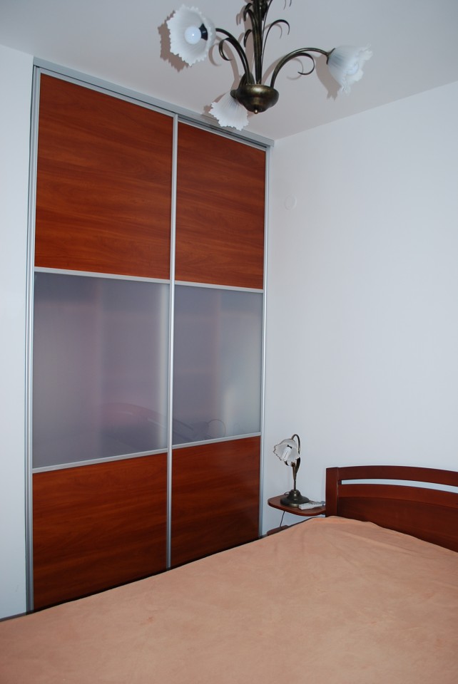 Bedroom in an apartment in Budva, Montenegro: double bed, built-in sliding wardrobe with frosted glass, and chandelier.