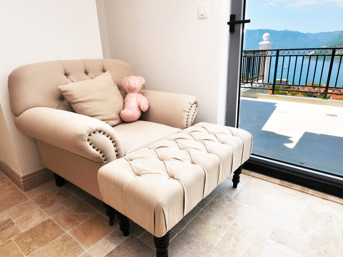 Armchair with ottoman in an apartment interior in Risan, Montenegro, with panoramic views of Kotor Bay and a terrace.