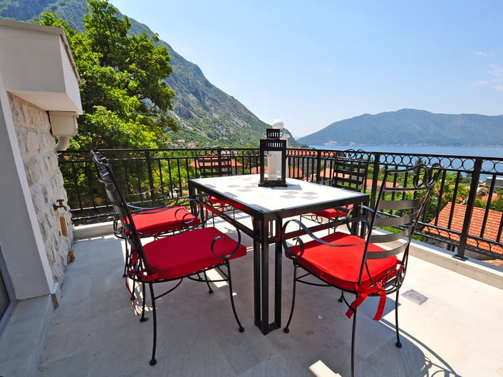 Terrace with wrought-iron furniture and a view of the Bay of Kotor in an apartment, Risan, Montenegro.