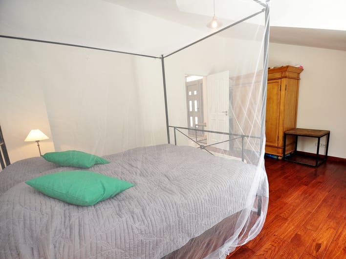 Bedroom with a canopy bed and wooden floor in an apartment for sale, Risan, Montenegro.