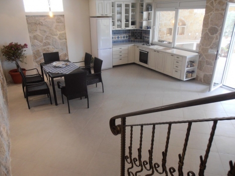 Kitchen-dining room with stone finishes and furniture in a villa, Luštica, Montenegro. Spacious interior with access to the terrace.