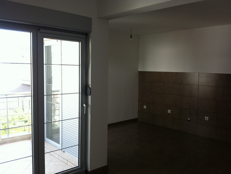 Kitchen interior in an apartment in Petrovac, Montenegro: dark tile, access to a balcony with panoramic glazing.