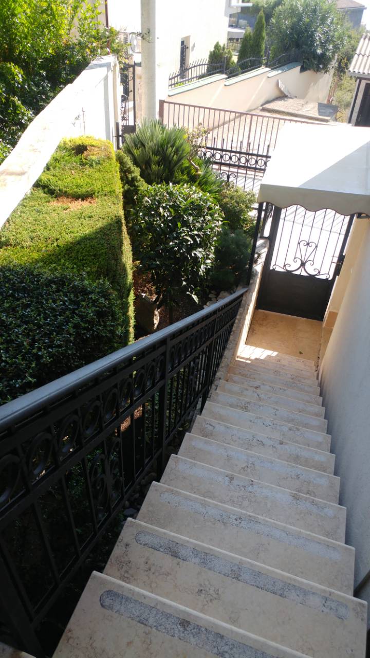 Stone staircase with wrought-iron railings and a green garden by the house in Ratac, Bar Riviera, Montenegro.