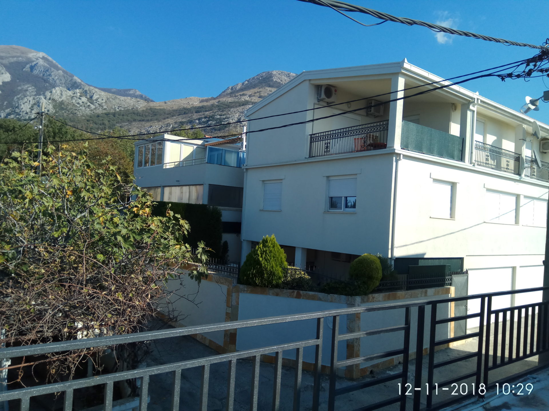 Two-story house with balconies and mountain views in Ratac, Bar Riviera, Montenegro. Building facade with landscaping.