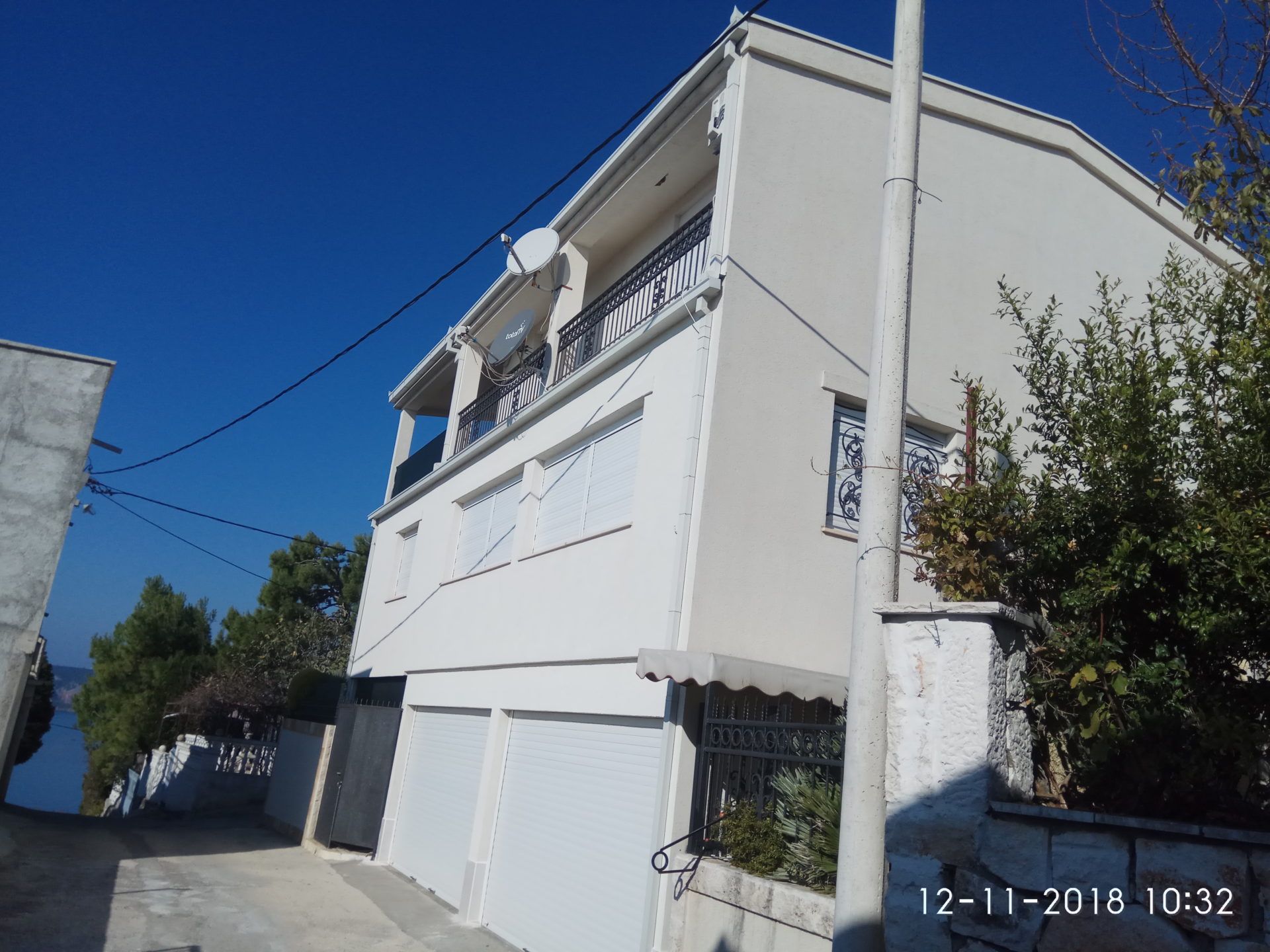 Three-story house with a garage and balconies in Ratac, Bar Riviera, Montenegro: street view of the building facade.