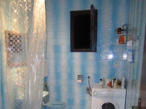 Bathroom in a house in Tivat, Montenegro: blue tiles, a shower cabin with a curtain, and a washing machine.