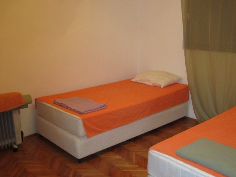 Bedroom with two single beds in a house in Tivat, Montenegro: parquet floor, light walls, and an oil heater.