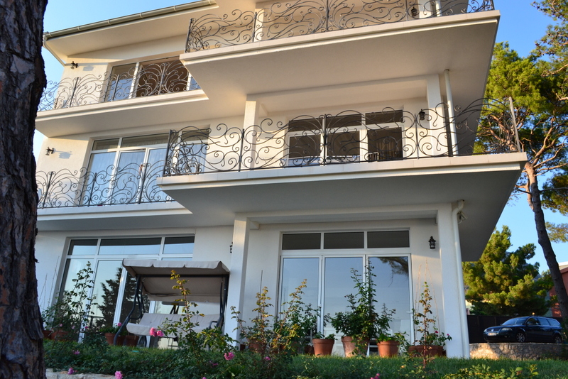 Three-story villa in Shushan, Montenegro, with wrought-iron balconies, panoramic windows, and a garden swing on the property.