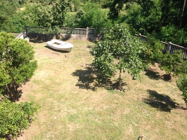 Green garden with fruit trees and a decorative boat on the grounds of a private house in Tivat, Montenegro.