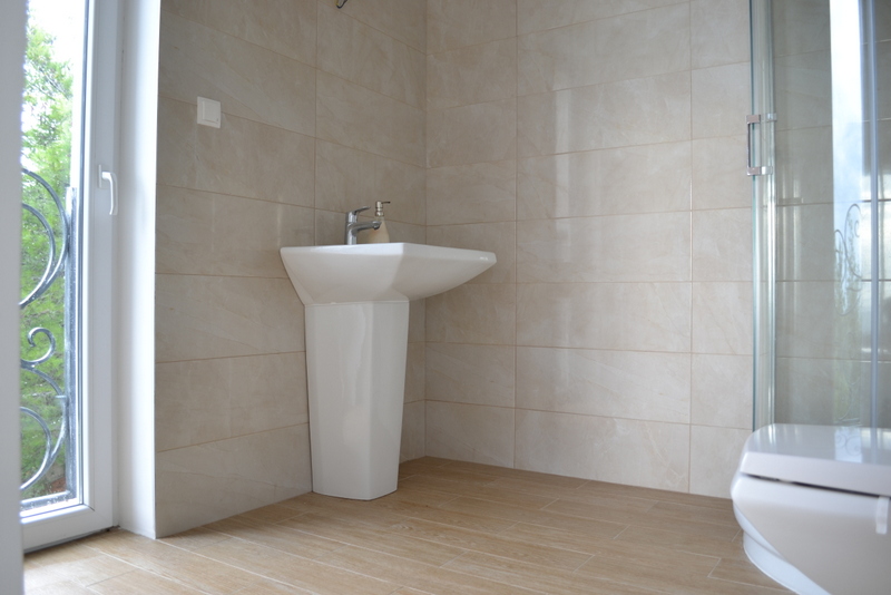 Bathroom with a shower cabin in a house in Shushan, Montenegro: light tiles, a sink, and access to the balcony.