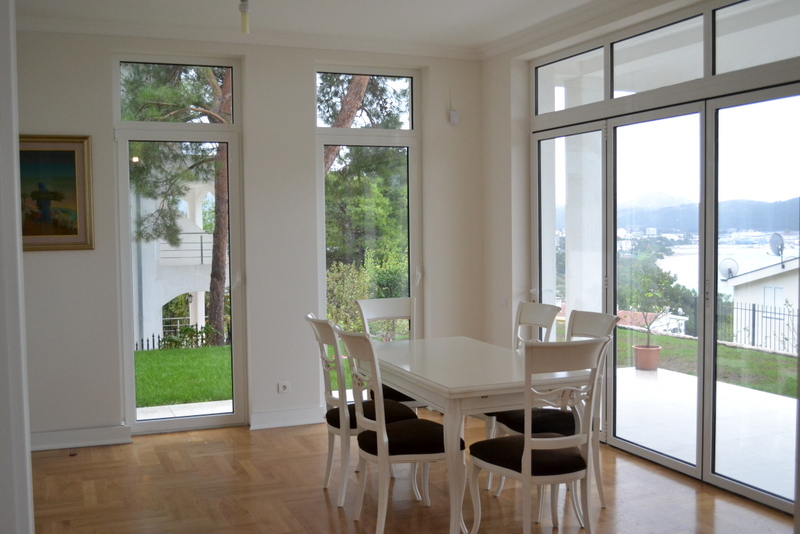 Bright living room with dining area and panoramic windows in a house in Shushan, Montenegro, sea and garden view.
