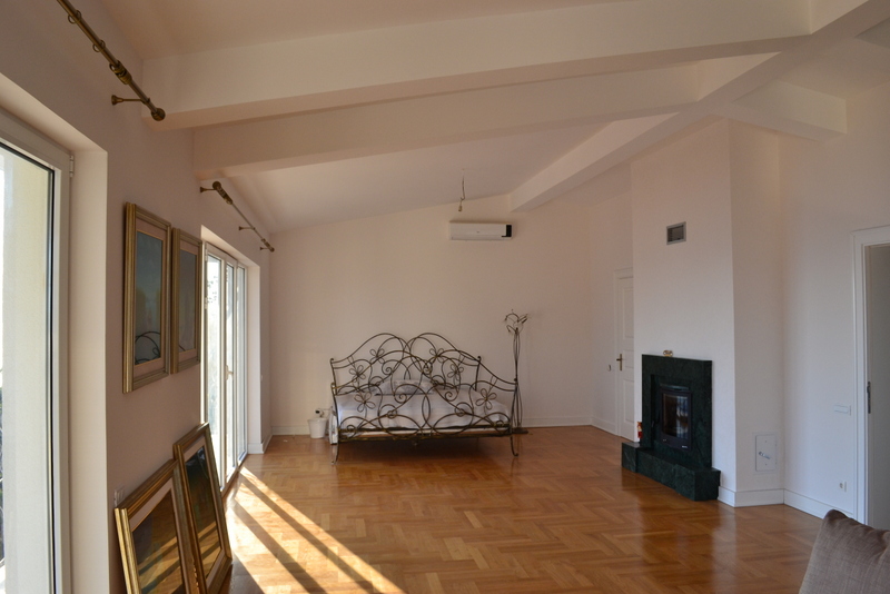 Bedroom in a house in Shushan, Montenegro: wrought-iron bed, parquet floor, stone-clad fireplace, and panoramic windows.
