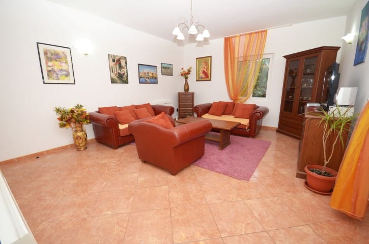 Living room in a house in Krašići, Montenegro: leather furniture, tiled floor, wooden cabinet, and warm-toned decor.
