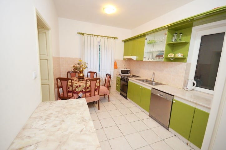 Kitchen with green cabinetry and dining area in a house for sale, Krašići, Montenegro: modern appliances and tile.