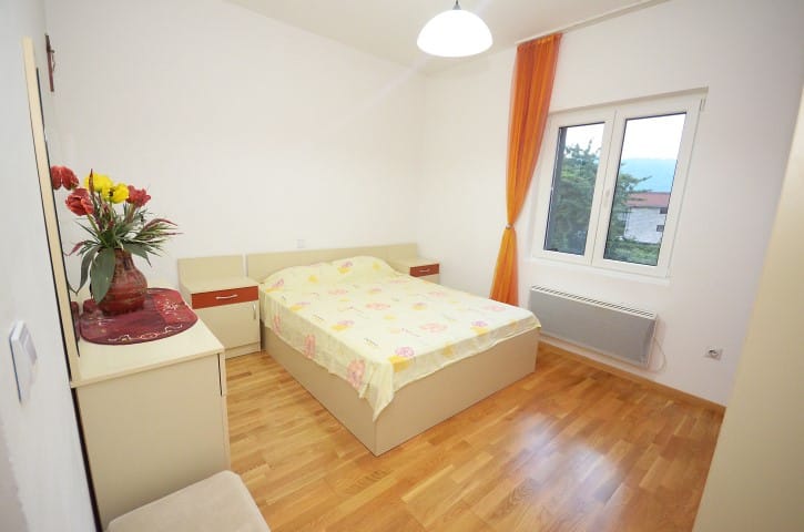 Bright bedroom with a double bed in a house in Krašići, Montenegro: parquet floor, window view, and a cozy interior.