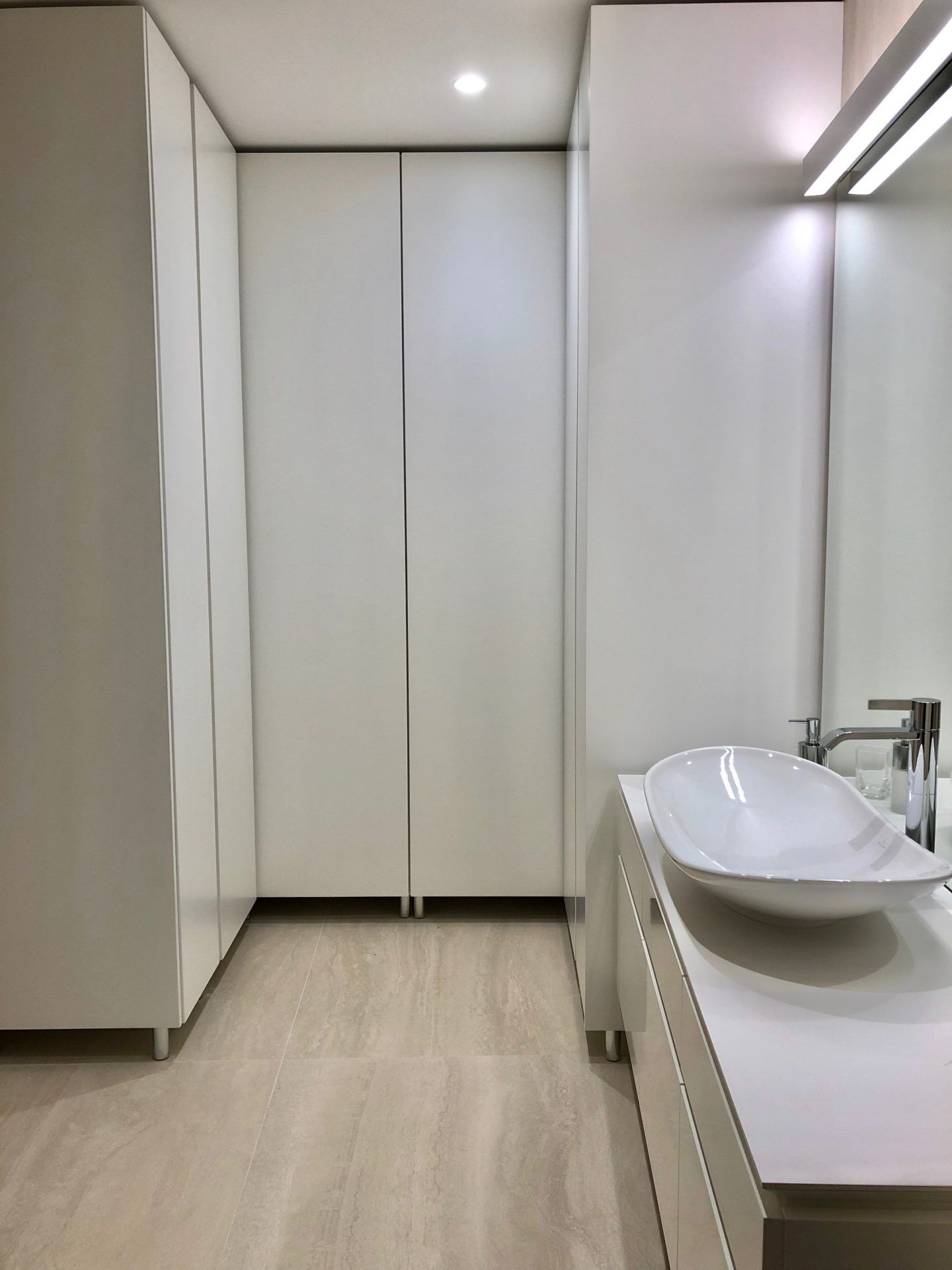 Modern bathroom in an apartment in Budva, Montenegro: white furniture, a vessel sink, and built-in cabinets.
