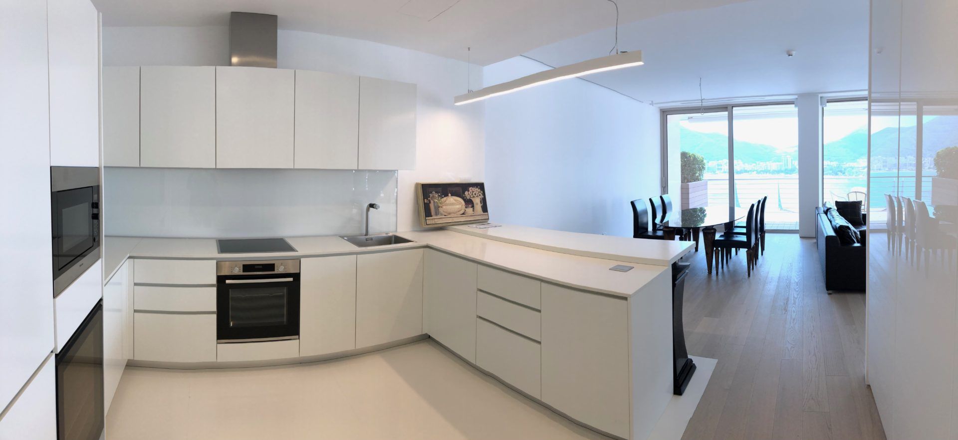 Modern white kitchen with an island and panoramic sea view in an apartment in Budva, Montenegro.