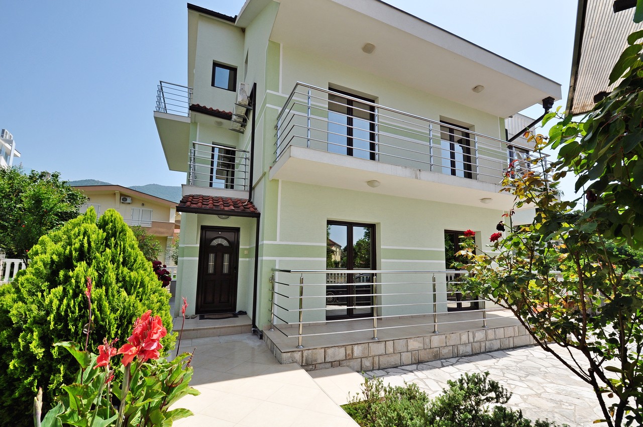 Two-story house with terraces and a garden in Tivat, Montenegro: modern facade, panoramic windows, and a well-kept grounds.
