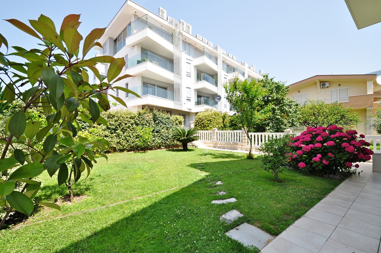 Modern residential complex in Tivat, Montenegro, with a well-kept green garden, lawn, and blooming hydrangeas.