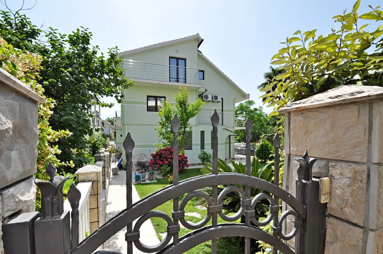 View of a two-story house with a balcony and ornate wrought iron gate in the foreground.
