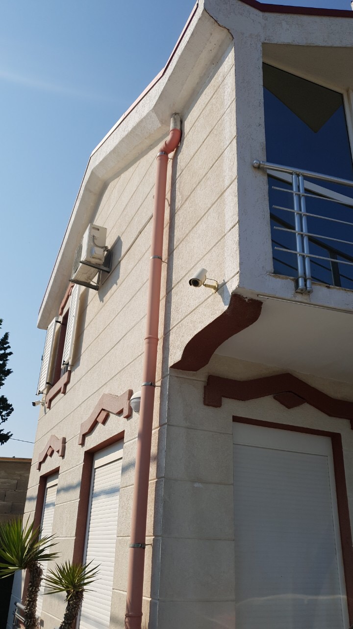 Facade of a two-story house in Tivat, Montenegro: light finish, balcony with railings, security shutters, and video surveillance.