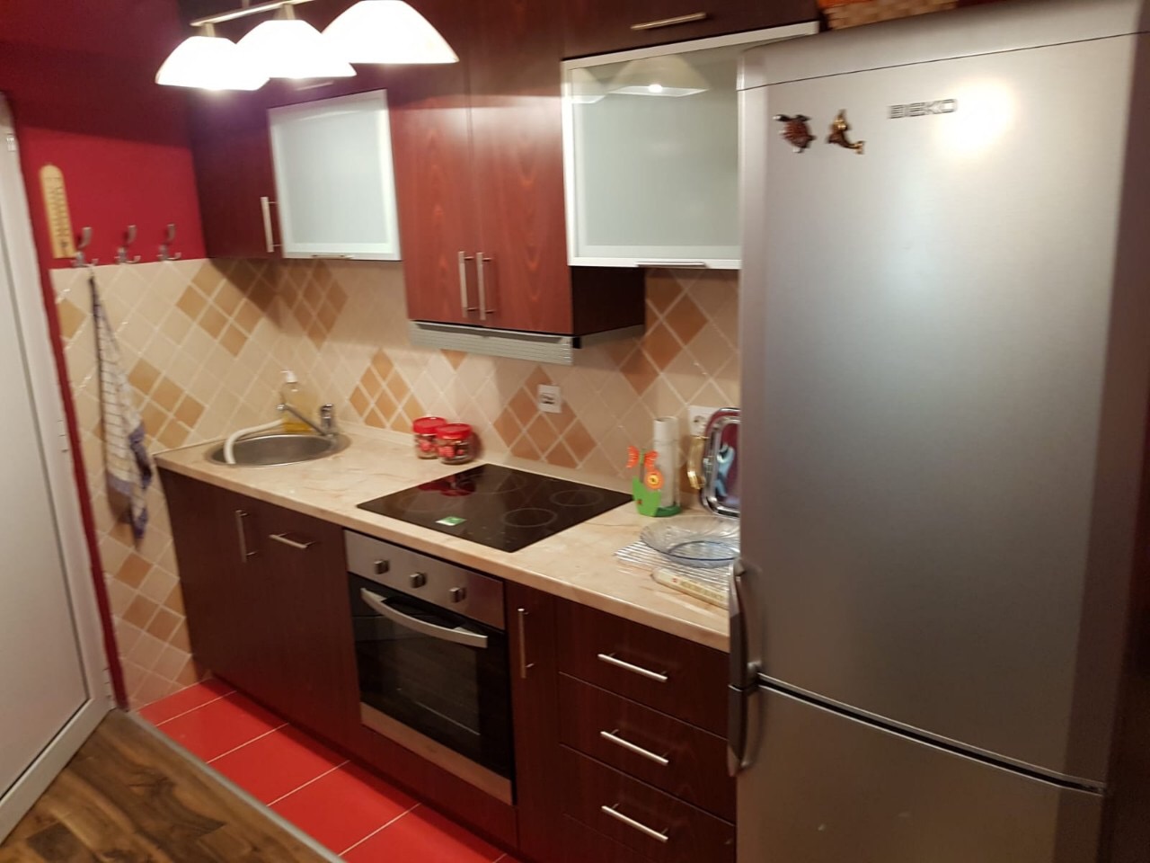 Kitchen in an apartment in Budva, Montenegro: dark cabinetry, built-in appliances, Beko stove and refrigerator, tiled backsplash.