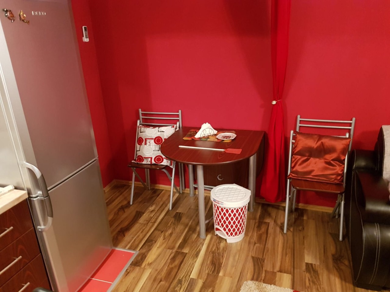 Kitchen in an apartment in Budva, Montenegro: dining area with a wooden table, chairs, and a refrigerator in the interior.