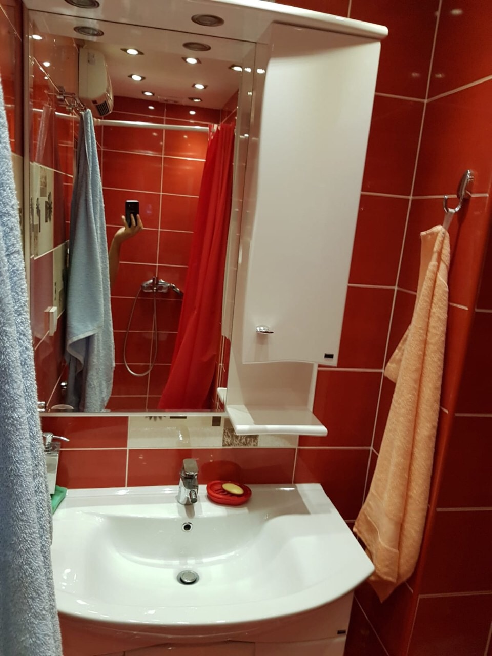Bathroom with red tiles, a white sink, and a mirror in an apartment for sale in Budva, Montenegro.