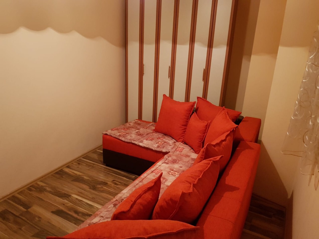 Cozy living room with a red corner sofa and built-in wardrobe in an apartment, Budva, Montenegro.