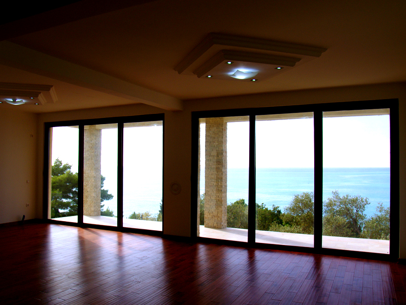 Living room with panoramic windows and sea view in a house, Sutomore, Bar Riviera, Montenegro: parquet flooring and stone columns.