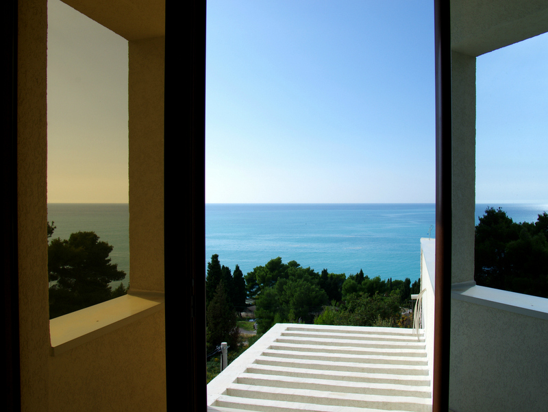 Sea view from the balcony of a house in Sutomore, Bar Riviera, Montenegro: panoramic landscape with a terrace and coniferous trees.