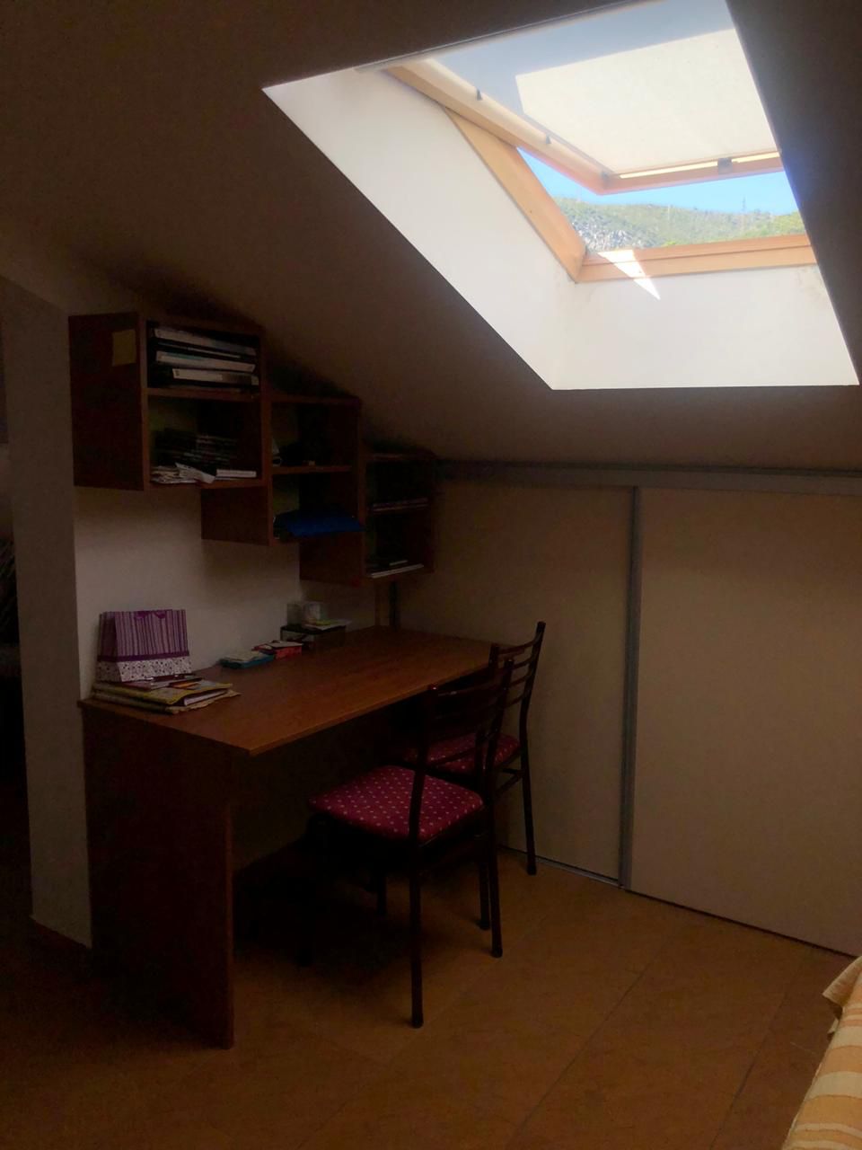 Work area in the attic bedroom of an apartment in Becici, Montenegro, with a desk and a skylight.