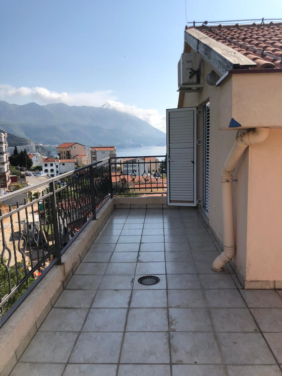 Spacious apartment balcony in Bečići, Montenegro, with panoramic views of the sea, mountains, and cityscape.