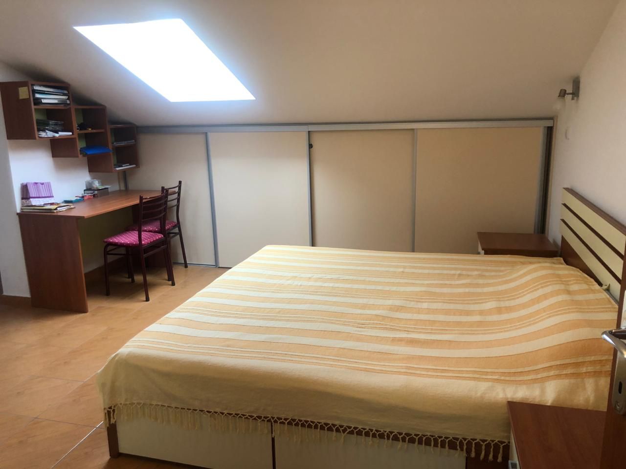 Bedroom in a loft apartment in Becici, Montenegro: a double bed, built-in wardrobe, and a desk by the window.