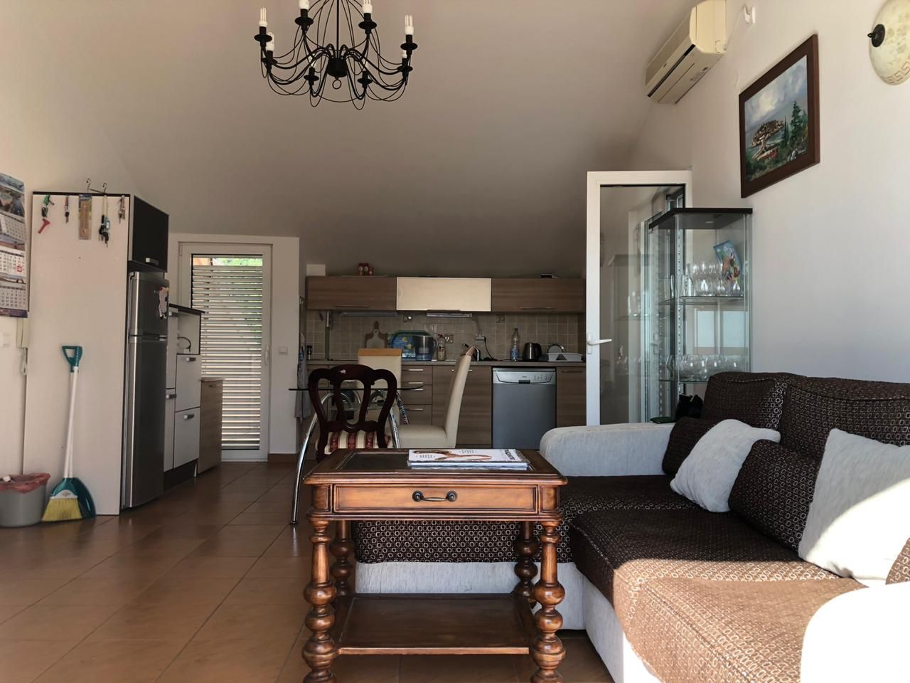 Living room with kitchen in an apartment in Becici, Montenegro: a soft sofa, wooden coffee table, and kitchen set with appliances.