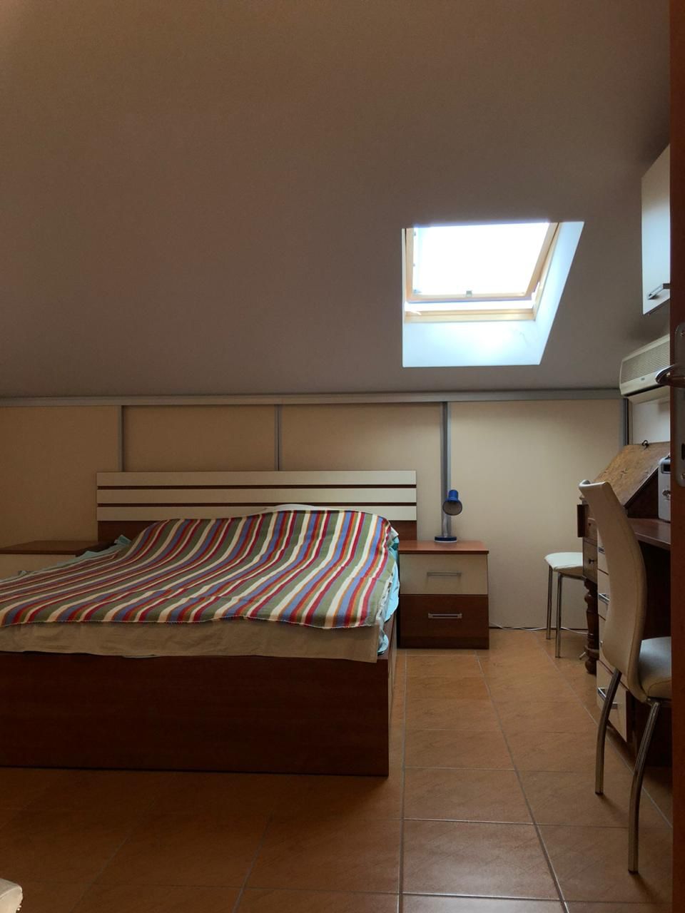 Bedroom in a loft apartment in Bečići, Montenegro: a double bed, a desk, and a skylight window.
